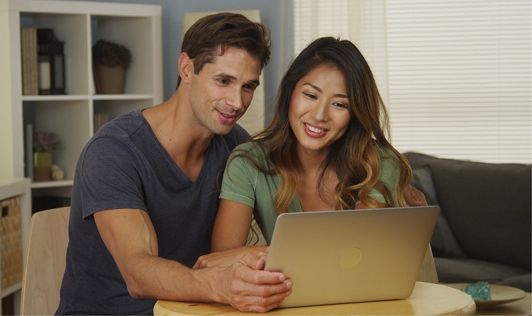 a couple happily researching on their laptop together