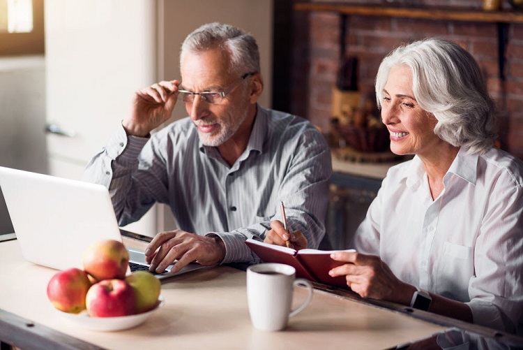a retired couple sits together, reviewing their finances