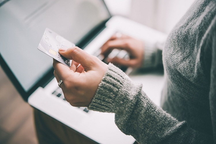 a credit card held up by a woman at her computer