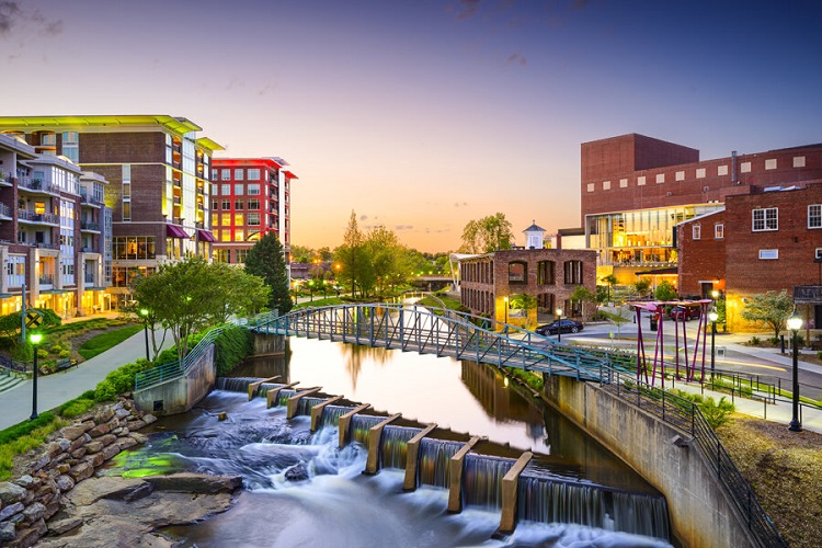 a view up the waterway running through an urban area of Greenville at dusk