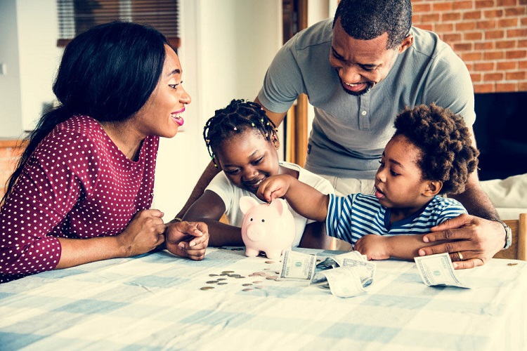a mother and father help their two children store money in their piggy bank